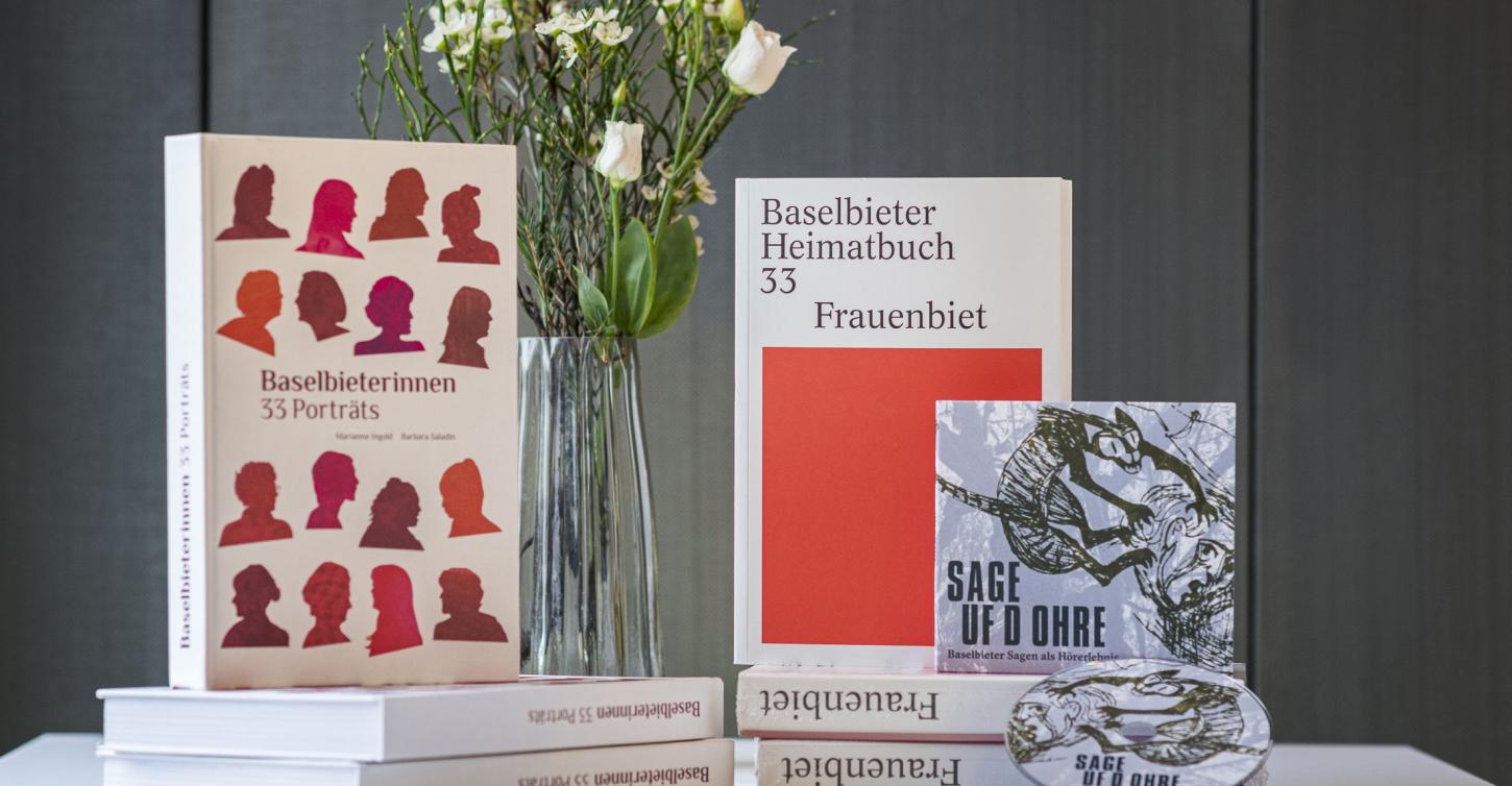 Verschiedene Publikationen von 2022 präsentiert auf Tisch mit Blumen